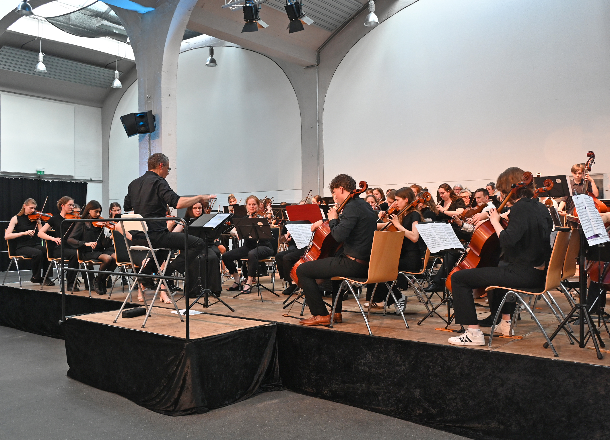Das Symphonieorchester musiziert auf der Bühne, während Gary Woolf dirigiert.