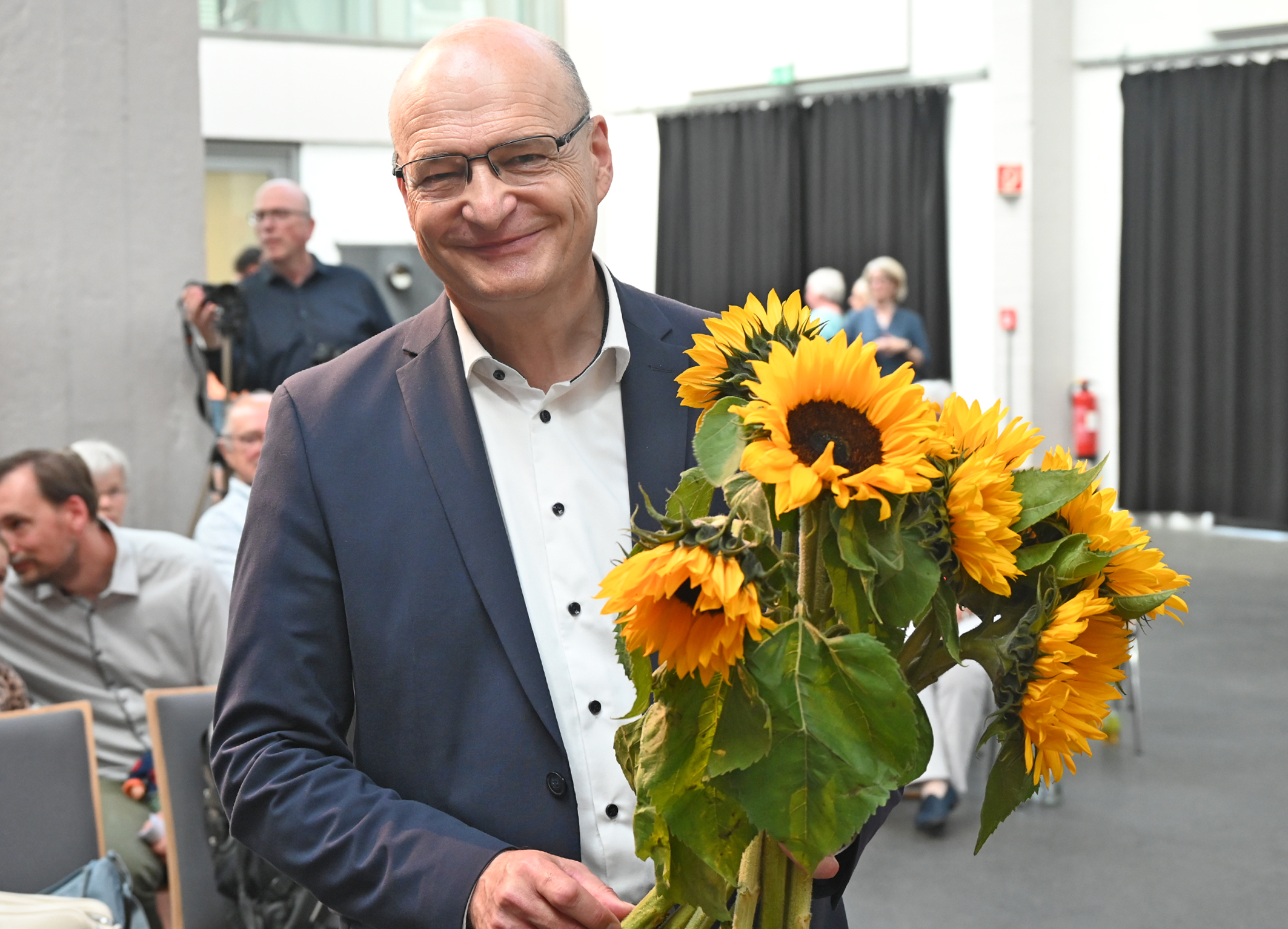 Dr. Martin Sommer hält die Sonnenblumen für die Musizierenden.
