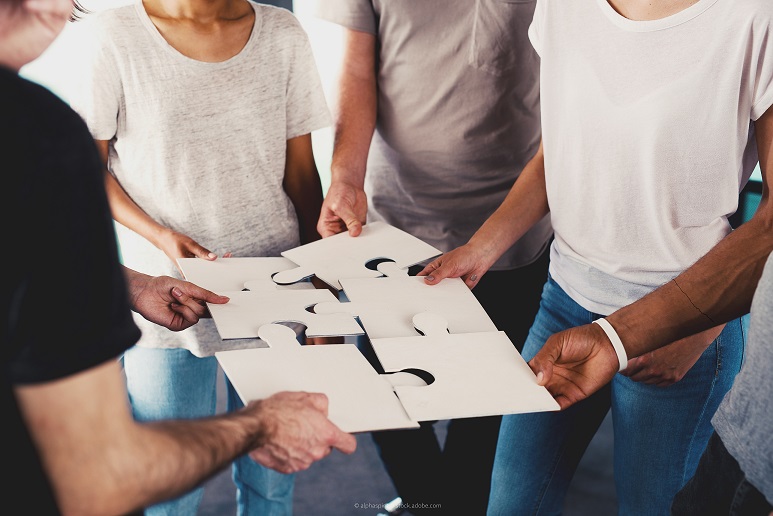 Foto mit vier Personen, die Puzzleteile zusammenfügen