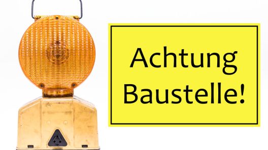 Links eine gelbe Warnleuchte. Rechts daneben ein Schild, auf welchem 