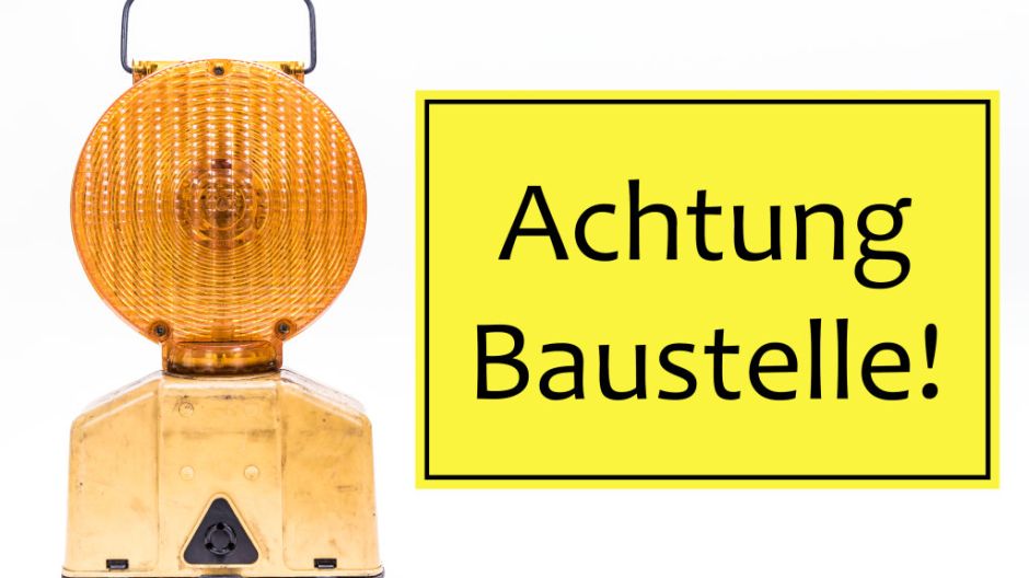Links eine gelbe Warnleuchte. Rechts daneben ein Schild, auf welchem "Achtung Baustelle" steht.